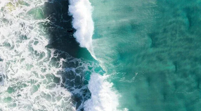 Aerial view of clear turquoise ocean water and waves, highlighting a marine environment ideal for diving and snorkelling.